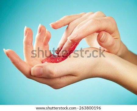 Woman's hands in body scrub on blue background
