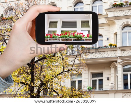 travel concept - tourist takes picture facade of house and yellow linden in Berlin in autumn on smartphone,