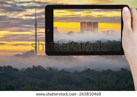 travel concept - tourist takes picture of yellow sunrise and morning fog in autumn city on smartphone, Moscow