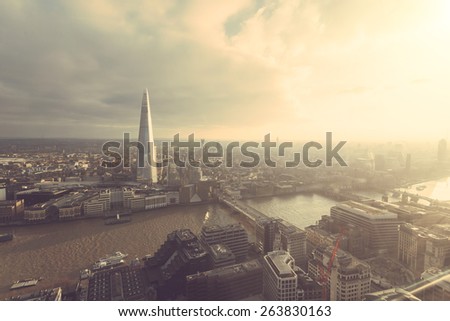 Aerial view of London with The Shard skyscraper and Thames river at sunset with grey clouds in the sky. Vintage filter applied.