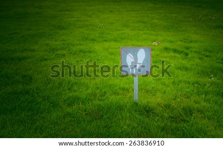The sign on the label "do not walk" on a green lawn.