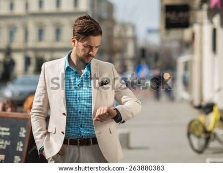 Smart casual outfit man downtown looking at his watch Royalty-Free Stock Photo #263880383
