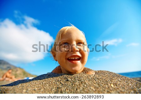 girl looks into the camera on the sunny beach over a blue sky