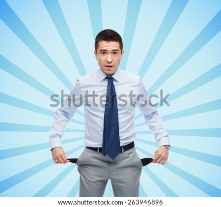business, people, bankruptcy and failure concept - surprised businessman showing empty pockets over blue burst rays background