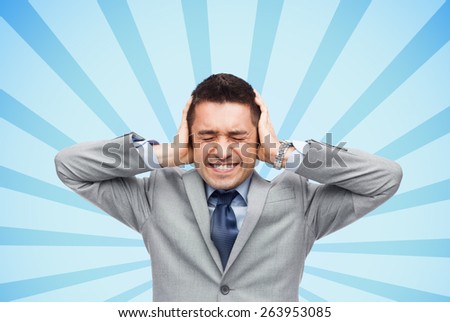 business, people, crisis and emotional pressure concept - businessman in suit covering his ears by hands over blue burst rays background