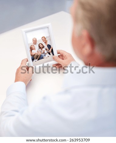 oldness, memories, nostalgia and people concept - close up of old man holding and looking at happy family photo