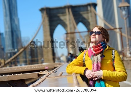 Beautiful young woman sightseeing on Brooklyn Bridge, New York, at sunny spring day