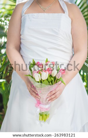 Bride in wedding dress with flower bouquet with tulips in her hands