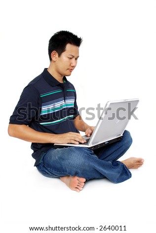 Asian male sitting with laptop on white background - face looking at computer