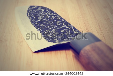 Japanese damascus carbon steel knife on wooden plank, close-up, toned picture