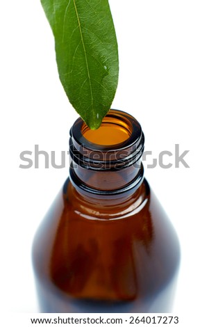 A fresh leaf with a drop of water above a glass bottle isolated on white background