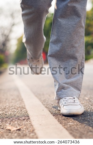 Legs of female jogger running outdoors: healthy lifestyle concept