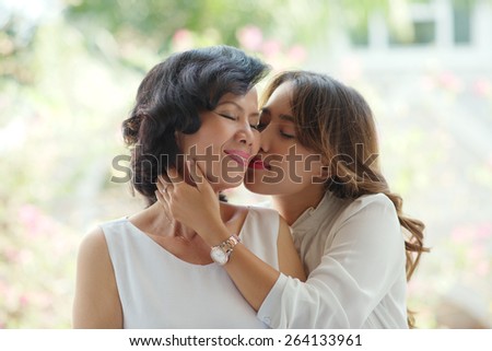 Adult daughter kissing her mature mother