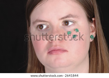 A smiling woman with green shamrocks on her cheek.