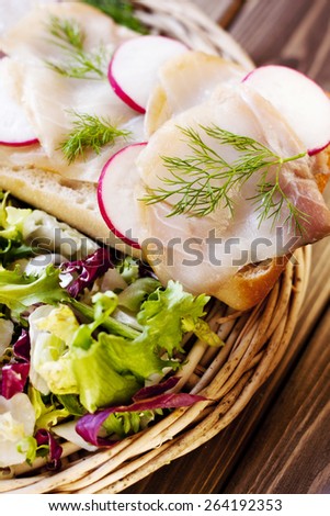 Sandwich with fish and vegetables on a wood background