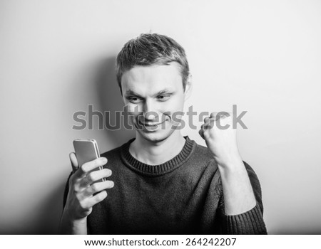 Closeup portrait of handsome young man, shocked surprised guy, opened mouth, eyes, by what he sees on his cell phone.