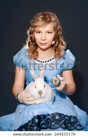 Little girl in a blue dress sitting on her lap rabbit