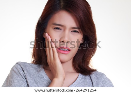 Teen woman pressing her bruised cheek with a painful expression as if she's having a terrible tooth ache.