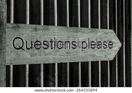 Wooden Direction Sign with the Words Questions Please overlaid in Black and White against a Corrugated Iron Background. Image could be used as a closing presentation slide in PowerPoint for example. 