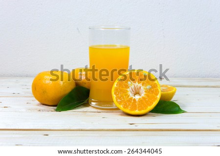 Glass of delicious orange juice and slices of orange on wooden table background