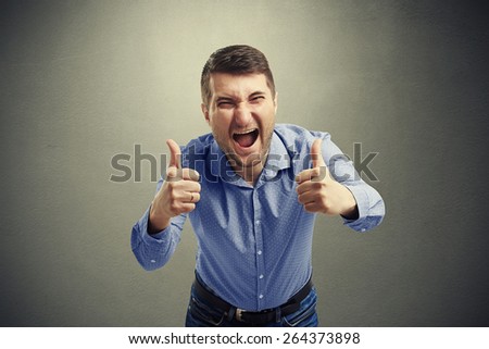 happy man showing two thumbs up and laughing over dark background