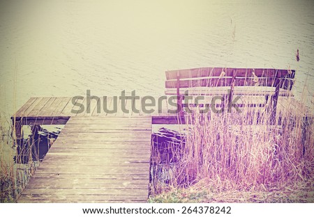 Vintage stylized photo of a wooden bench at the lake.