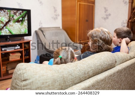 Family at home, watching lcd tv sitting on sofa, three people