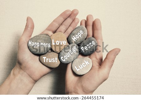 Inner balance concept: hands holding stones with the words happiness, love, trust, courage, hope, peace and luck. Royalty-Free Stock Photo #264455174