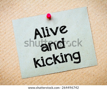 Alive and kicking Message. Recycled paper note pinned on cork board. Concept Image