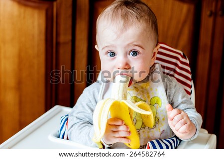 Cute baby eating banana Royalty-Free Stock Photo #264582764