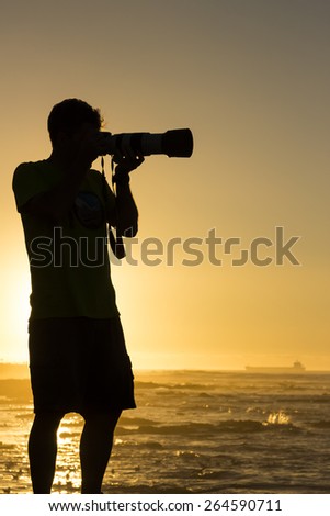 Photographer taking photographs of birds at sunset