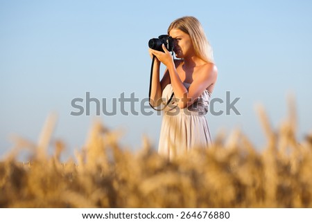 Young woman photographing in wheat field