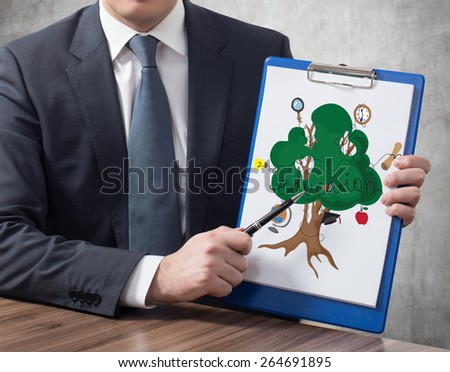 businessman in office holding clipboard with education tree