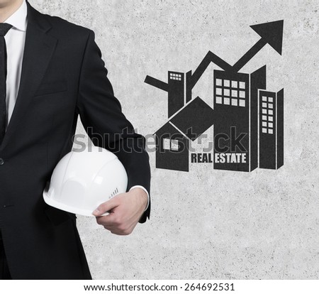 businessman with helnet and real estate symbol on wall