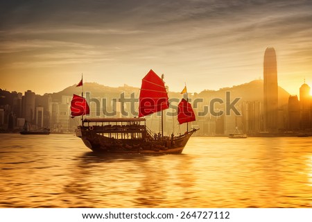 Sunset skyline of Hong Kong with traditional cruise sailboat at Victoria harbor