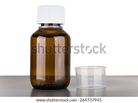 Bottle of cough syrup and volumetric capacity isolated on white background