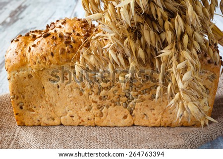 Fresh bread with sunflower seeds and ears on burlap