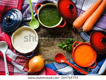 Different kinds of soups - sprinach soup, french onion cream-soup and carrot cream-soup on the table. Toned image.