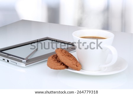 Close up image of cup of coffee with cookies. digital tablet on the table behind