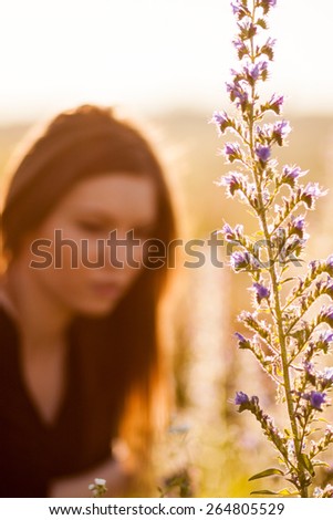 Beautiful wild flower with beautiful, blurred girl with long, straight hair posing in the background