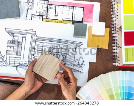 Top view of hands working with architecture hand-drawn sketch on creative workspace