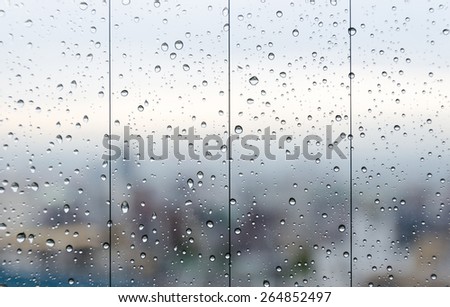 Raindrops on glass window overlooking the City on background