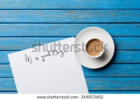 Cup of coffee and inscription on paper on wooden table.