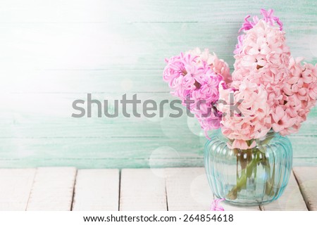 Background with fresh pink, violet hyacinths in vase in ray of light on white wooden planks. Selective focus. Place for text. 