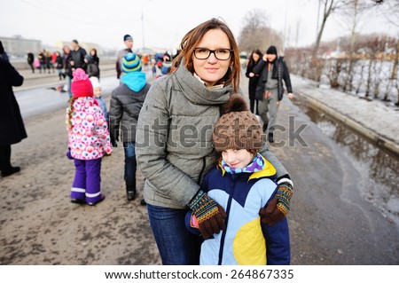 Mother and her little daughter walking in city on cold weather