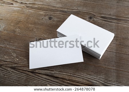 Blank white business cards on a dark wooden background. Mockup for branding identity. Shallow depth of field.