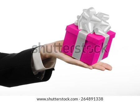 The theme of celebrations and gifts: hand holding a gift wrapped in pink box with white ribbon and bow, the most beautiful gift isolated on white background in studio