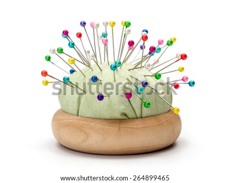 Wooden pincushion full with with colorful pins Royalty-Free Stock Photo #264899465