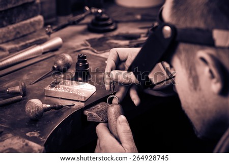 Craft jewelery making.  Ring repairing. Putting the diamond on the ring. Monochrome cream tone. Black and white photography. Royalty-Free Stock Photo #264928745