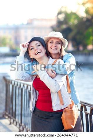 Two beautiful girls laughing and hug in the city outdoor